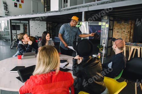 Preview: African american man in casual wear standing near the glass office wall with financial points