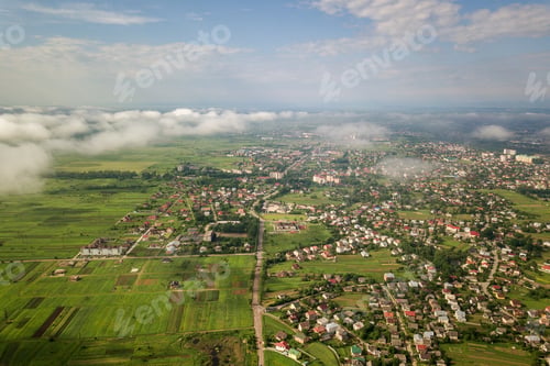 Preview: Aerial view of white clouds above a town or village with rows of buildings and curvy streets