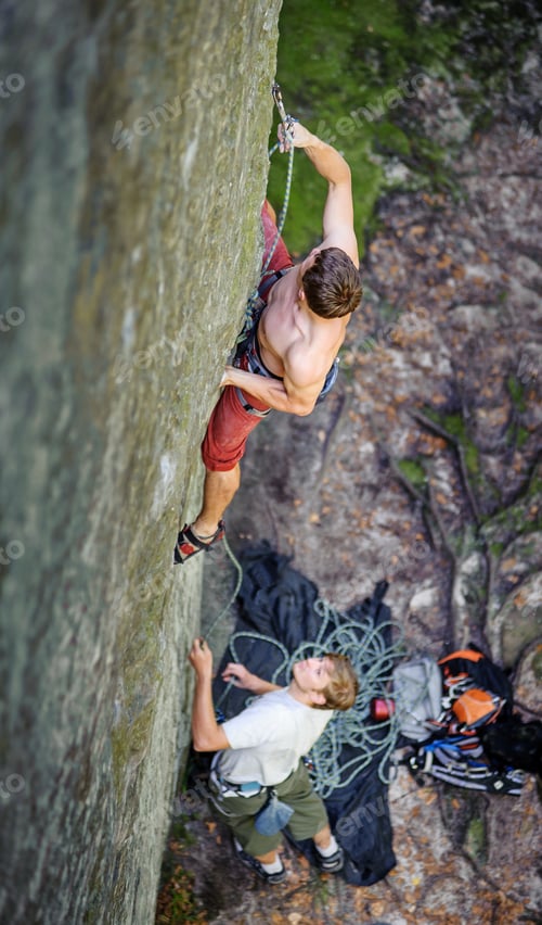Preview: Muscular rock climber climbs on overhanging cliff