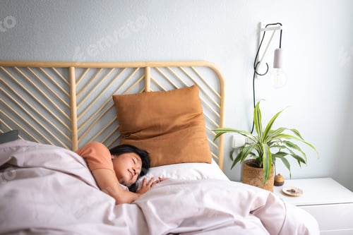 Preview: Teen Asian female lying down in cozy bed sleeping at home big bright bedroom. Lifestyle.