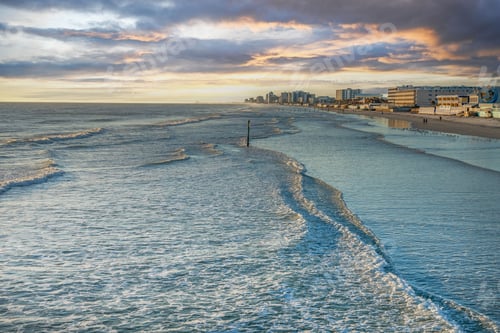 Preview: Coastal cityscape at sunset with gentle waves.