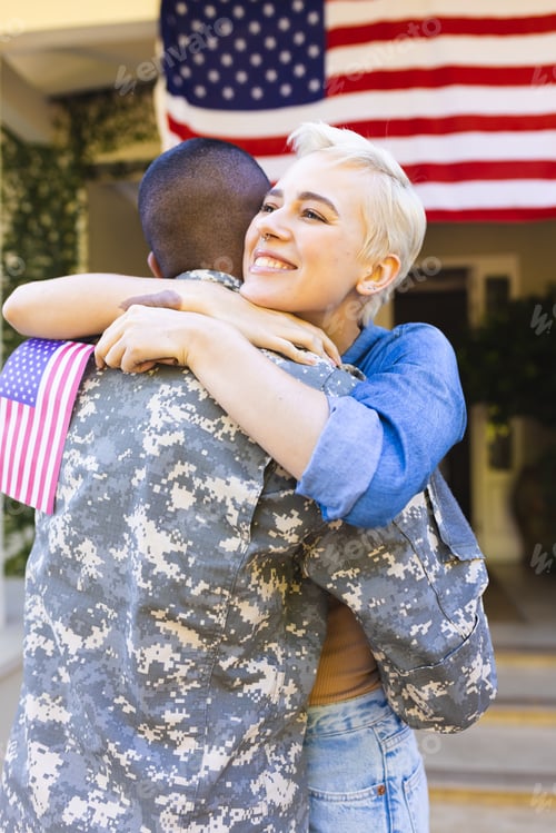 Preview: Happy caucasian woman and biracial male american soldier embracing outside the house