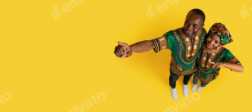 Preview: Loving black spouses pointing at copy space on yellow