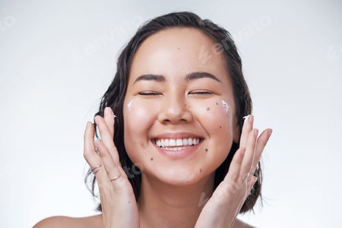Preview: Cropped shot of a beautiful young woman applying moisturiser to her face