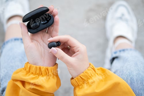 Preview: Female hands touching a portable gadget headphones.