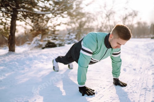 Preview: Young sportsman doing workout in forest at snowy winter day. Outdoor fitness, cardio exercises.