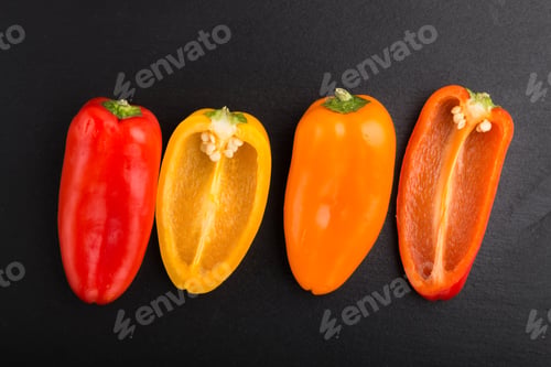 Preview: yellow, red, orange sweet peppers on a black slate background. top view, close up.