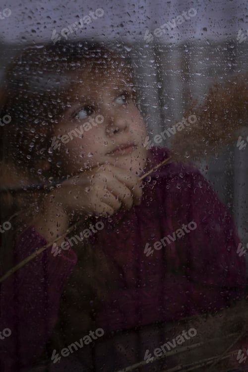 Preview: Contemplative Child Gazing Out Rainy Window at Home