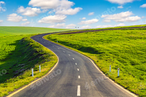 Preview: Asphalt road between green farm fields with blue sky and clouds