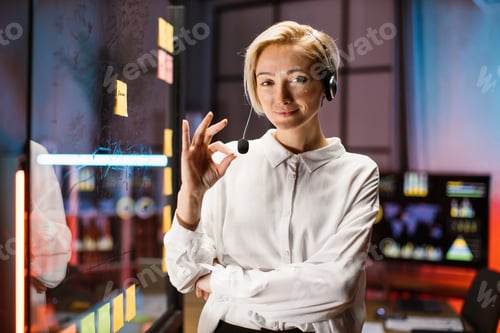 Preview: Caucasian woman in headset, posing near transparent glass board with marker pen