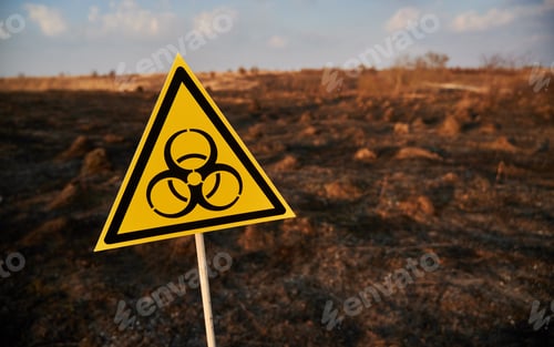 Preview: Yellow biohazard sign installed in scorched field with burnt anthills