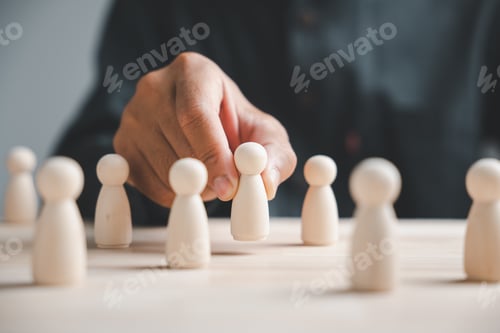 Preview: Hand placing wooden figure in front of other figures. Concept of leadership, team, selection, or