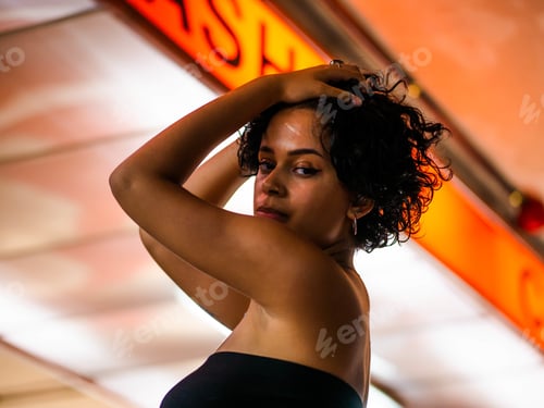 Preview: Closeup portrait of a stylish young female with a curly hair posing wearing a strapless top