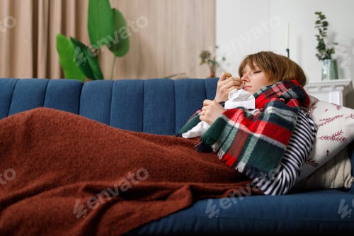 Young unhappy woman lying on the couch with a cold. Girl is sick on seasonal respiratory diseases