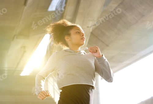 Preview: Young woman running in urban environment