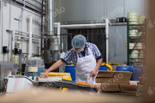 Preview: Man packaging vegan cheese in warehouse
