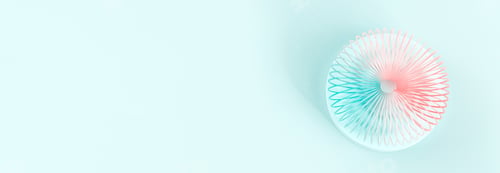 Preview: Colorful pastel color rainbow spiral plastic toy on turquoise background on podium