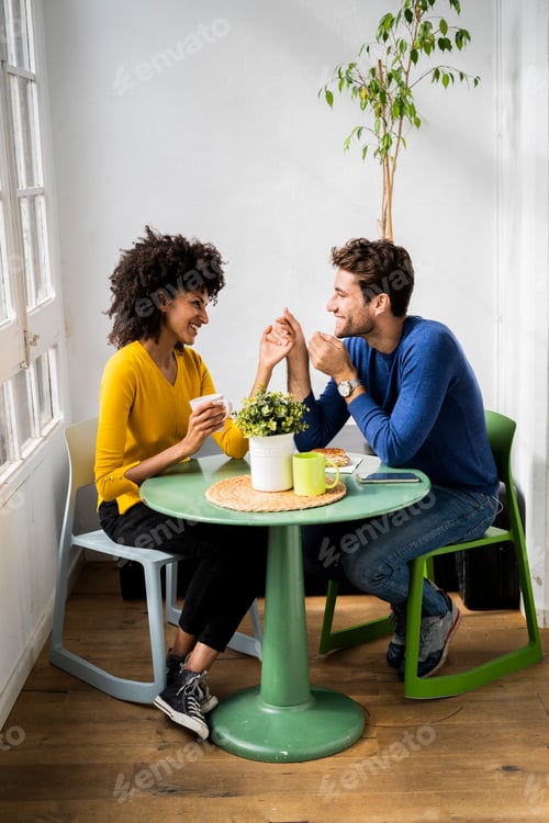 Preview: Happy affectionate couple sitting at table at home
