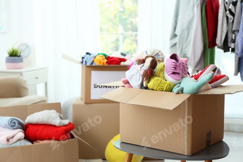 Preview: Donation box with clothes and toys on table indoors. Space for text