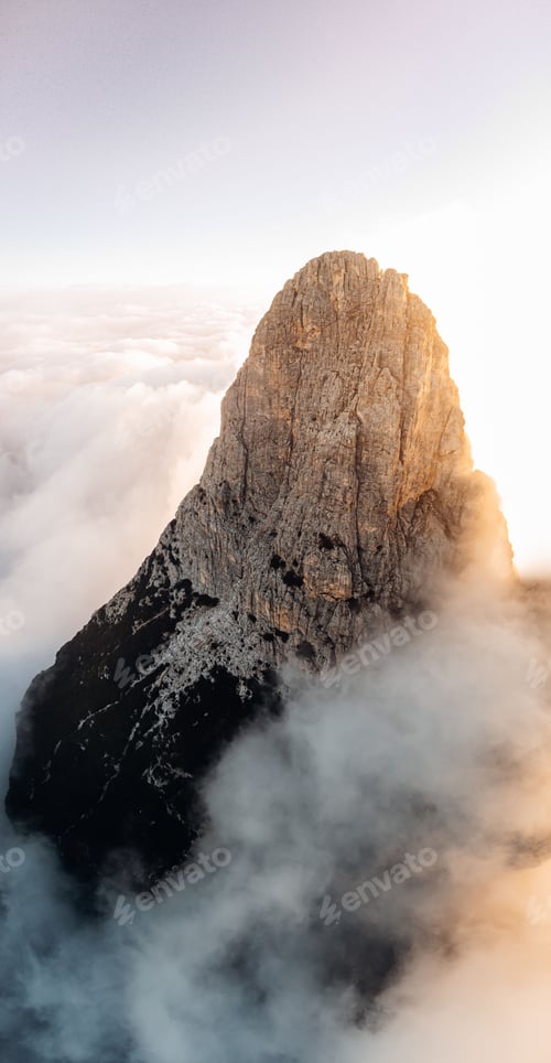 Preview: Aerial vertical shot of the summit of the Dolomites rising in a cloud surface during sunset