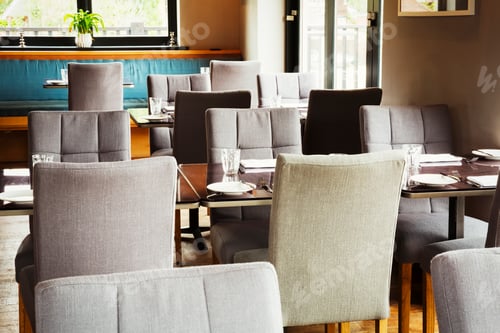 Preview: View of tables and grey upholstered chairs in a restaurant.