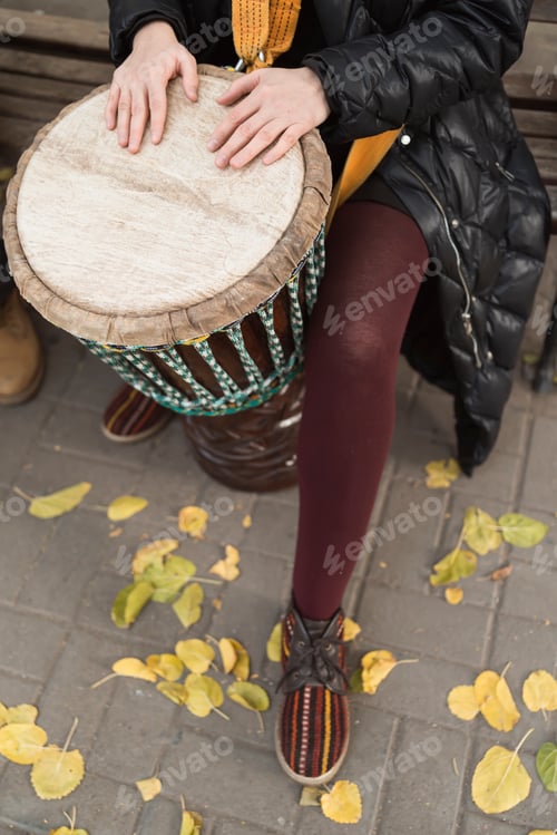 Preview: European woman playing an African drum djembe outdoors in autumn