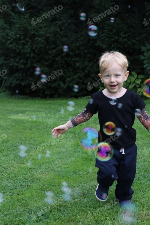 Preview: Toddler runs after soap bubbles on a green grass