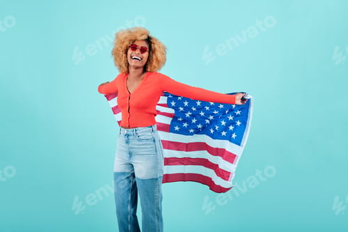 Preview: Happy afro woman with the American flag while standing on an isolated background.