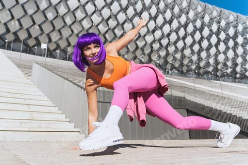Preview: Carefree active woman dancer wearing colorful sportswear having fun on the street