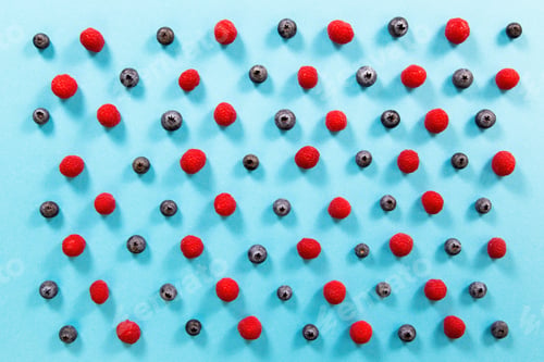 Preview: Fresh raspberries and blueberries alternately arranged on blue background