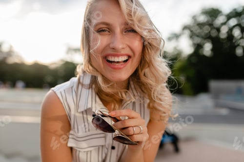 Preview: close-up portrait of young attractive stylish blonde woman in city street in summer fashion