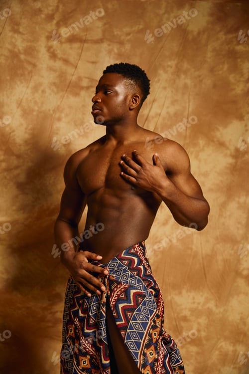 Preview: Young handsome man showcasing confidence and strength in an artistic pose against a warm backdrop