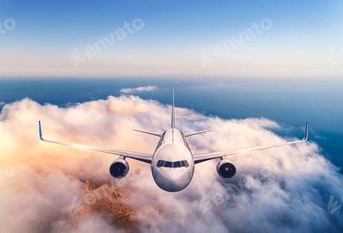 Preview: Airplane is flying over the clouds at sunset in summer. Aircraft