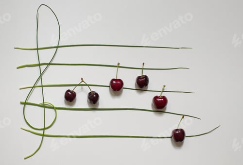 Preview: Concept photo of musical staff with cherries and herbs on white background