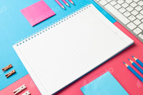 Preview: Composition of notebook with copy space, laptop and school equipment on blue and pink surface