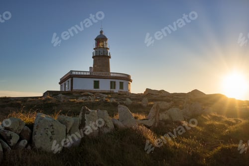 Preview: Corrubedo lighthouse surrounded by rocks and grass under the sunlight in Spain