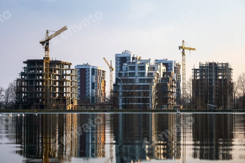 Preview: Tower cranes and high residential apartment buildings under construction on lake shore. Real estate