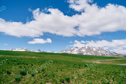 Preview: Green pastures at the foot of snowy mountain peaks