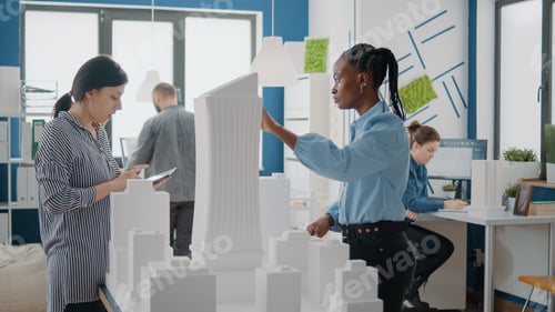 Preview: Team of multi ethnic architects using digital tablet and building model to design construction