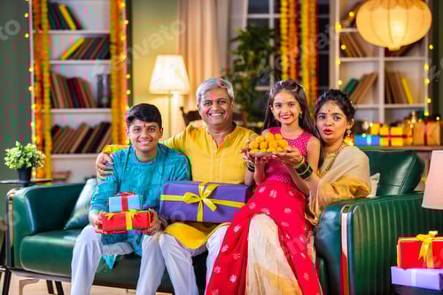 Preview: Indian family siutting with gift box on sofa on diwali festival night