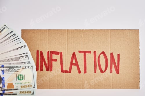 Preview: World inflation concept. Cardboard with word inflation and usd banknotes