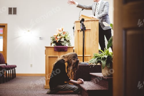 Preview: View of a female sitting on the floor of a church while bowing and praying during a religious mass