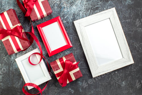 Preview: Overhead view of empty picture frames and gift boxes tied with ribbon on dark background