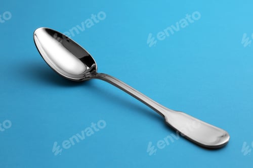 Preview: Clean empty tea spoon on blue background