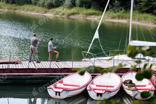 Preview: Rear view of son and father fishing