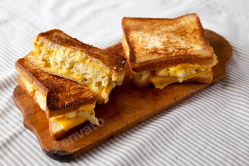 Preview: Homemade Grilled Macaroni and Cheese Sandwich on a rustic wooden board, low angle view.