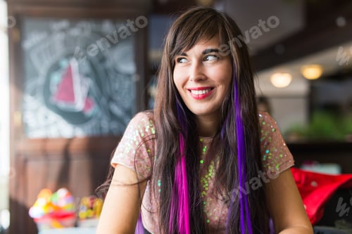 Preview: Young stylish trendy woman with multi-coloured strand in hair sits in cafe