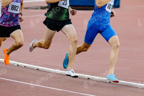 Preview: three runners athletes on middle distance running together in track stadium