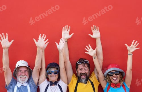 Preview: Group of happy people senior and middle aged with arms outstretched standing against a red wall.
