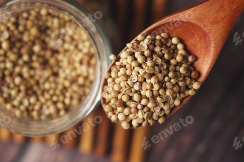 Preview: Coriander seeds in a wooden spoon on a kitchen table